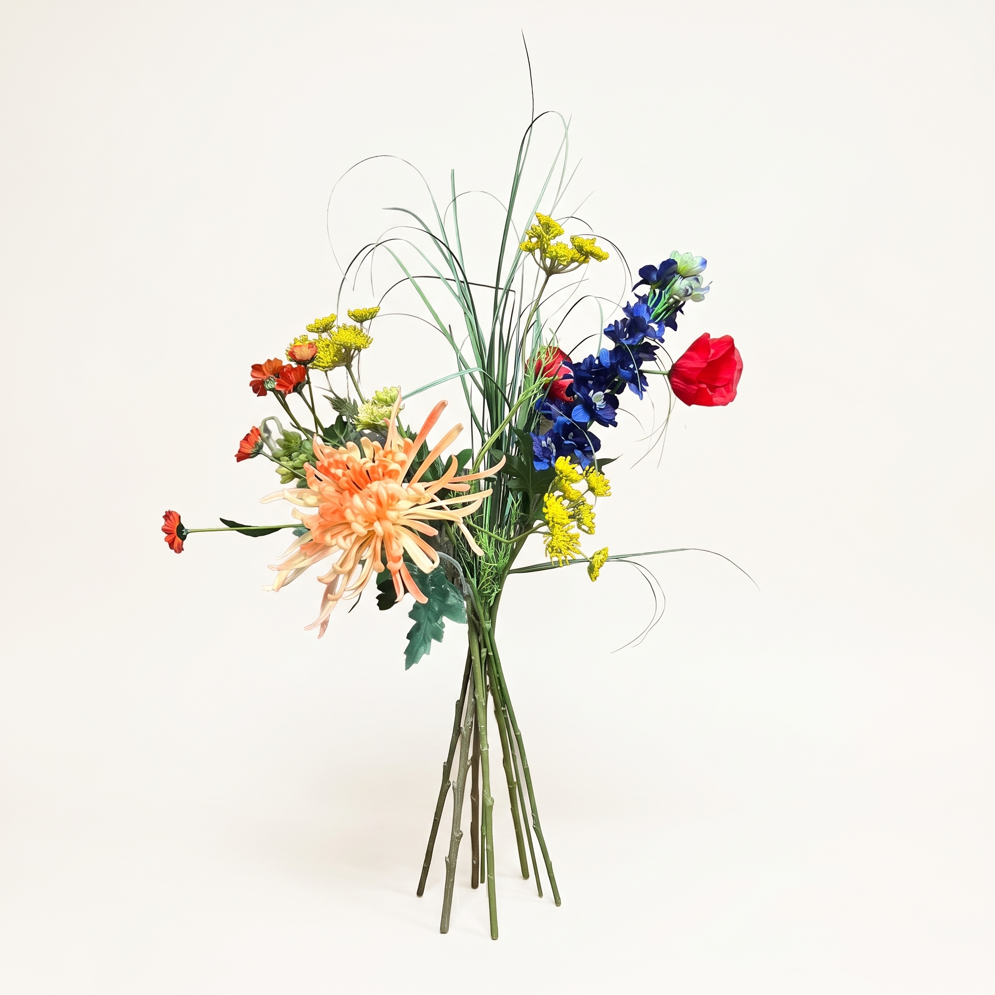 Kleurrijk zijden kunstboeket met veldbloemen, siergras en een oranje chrysant op een witte achtergrond