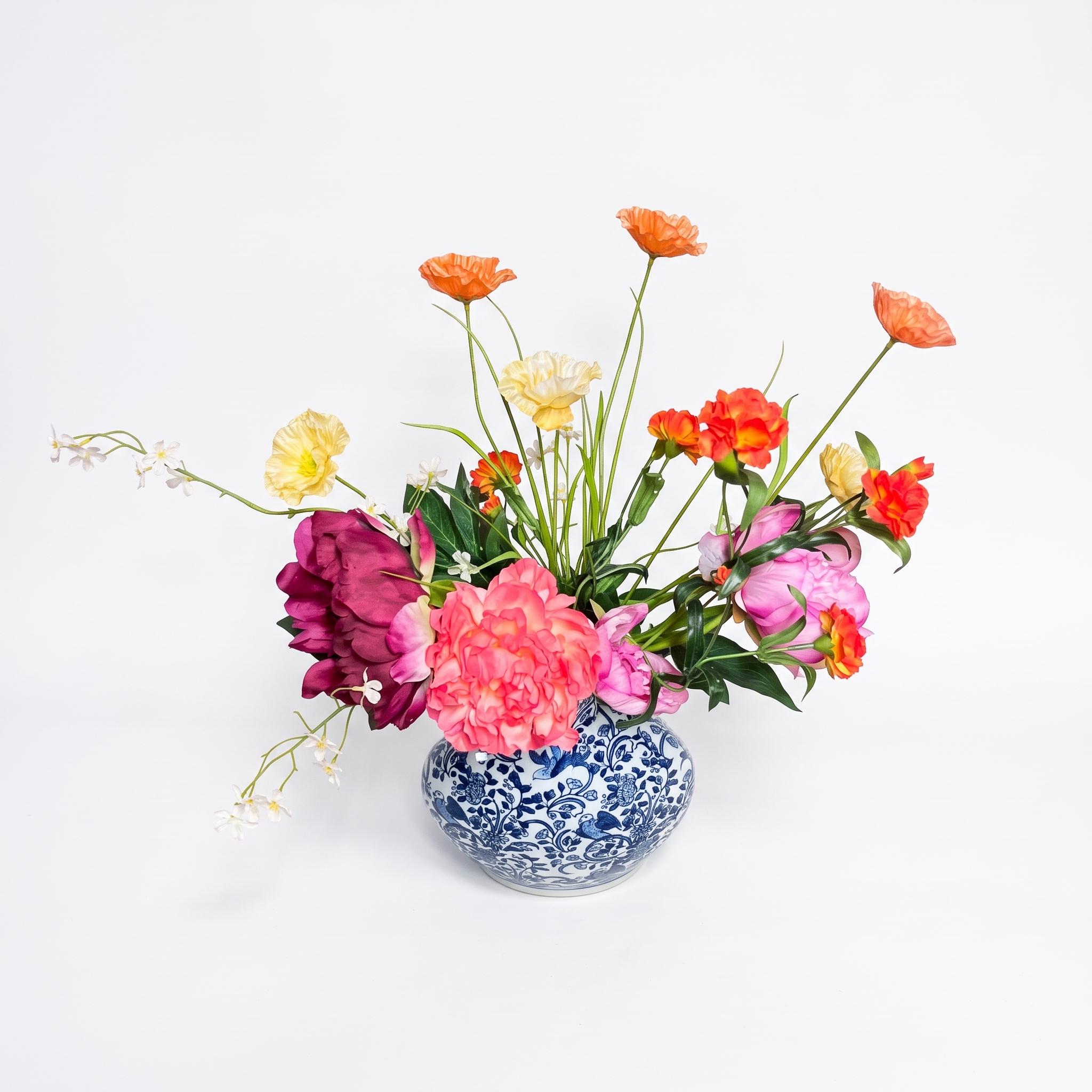 Een bovenaanzicht van het gemengde kunstbloemen boeket in een blauw-witte vaas, toont de diepte en het volledige volume van de bloemstukken.